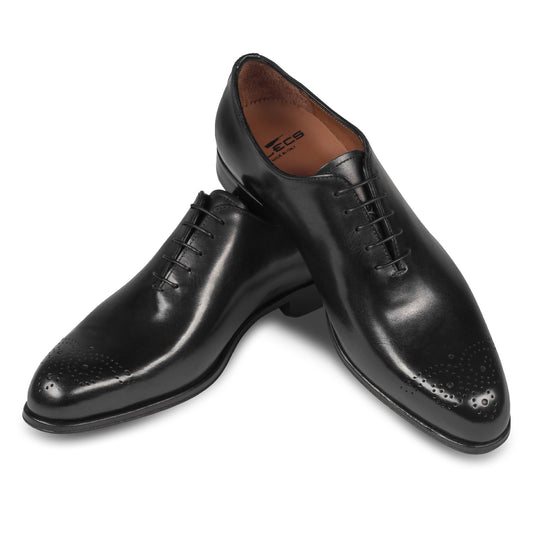 Anzugschuhe von FLECS, Onecut / Wholecut Brogue Schnürer in schwarz, Durchgenäht. Paarweise Ansicht Schuhe überkreuzt aufgestellt. Bei Sisento.